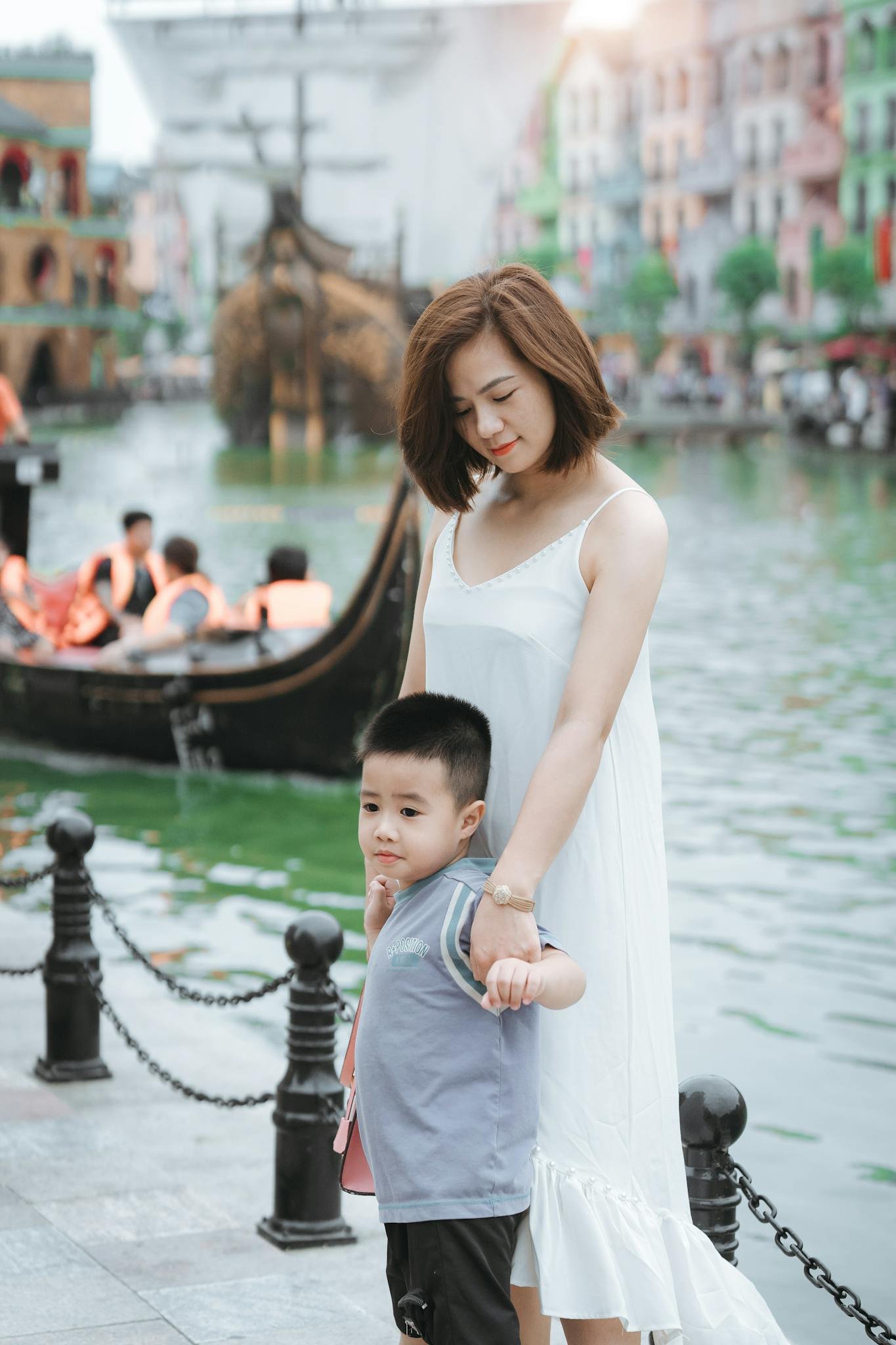 A mother and son enjoying a peaceful day by the canals with gondolas in the background.